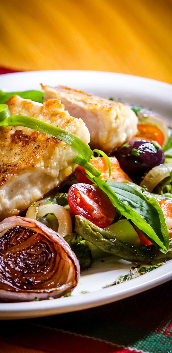A delicious plate of grilled chicken with roasted Mediterranean vegetables and fresh herbs, perfect for a healthy meal.